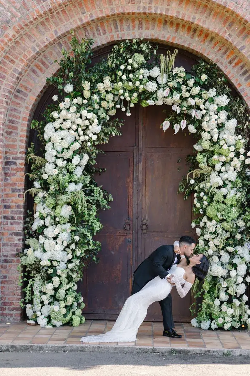 Grand brick arch framed with white florals for garden wedding in Antioquia