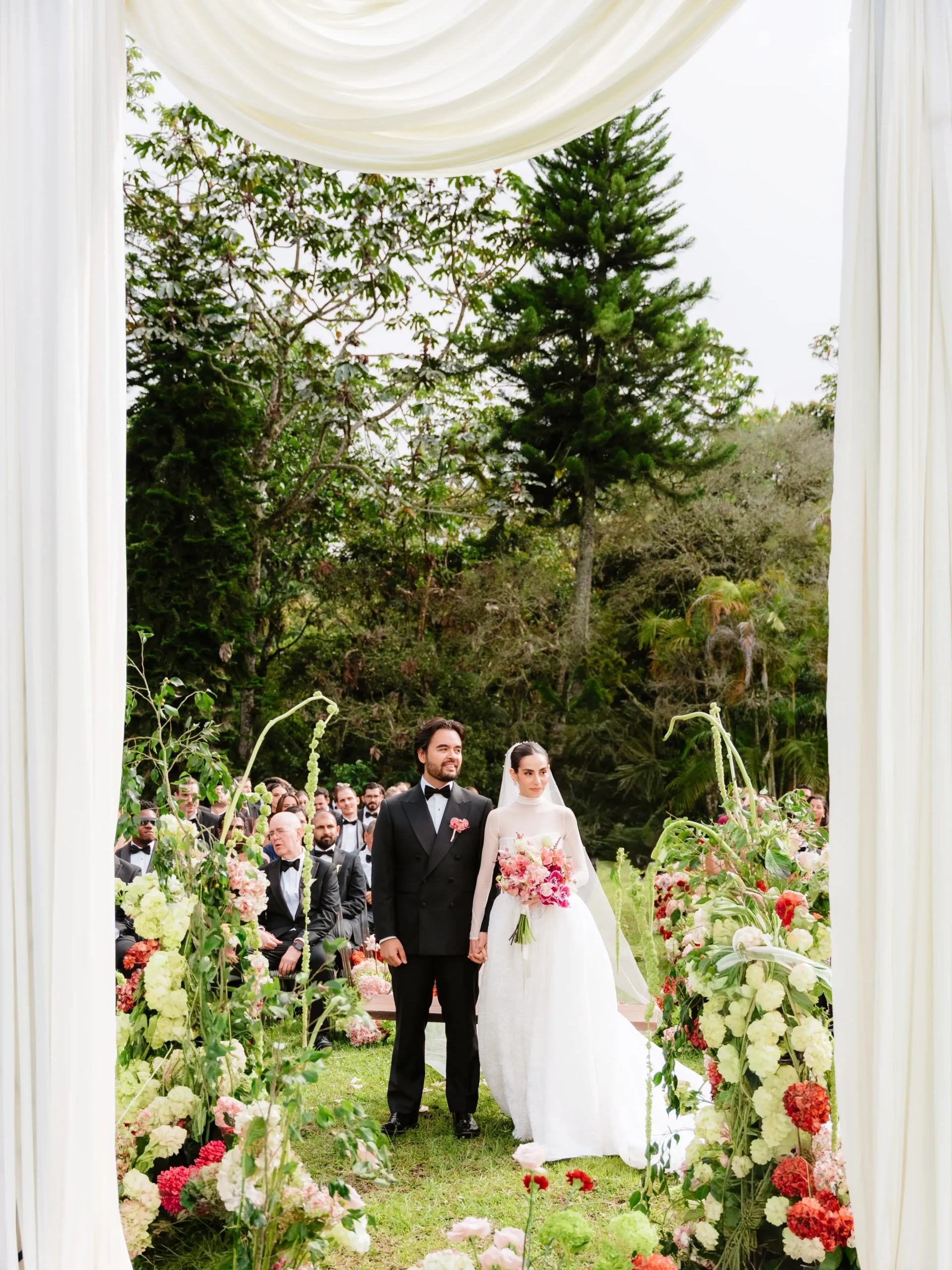 Newlyweds standing at the floral ceremony altar at an outdoor wedding in Rionegro